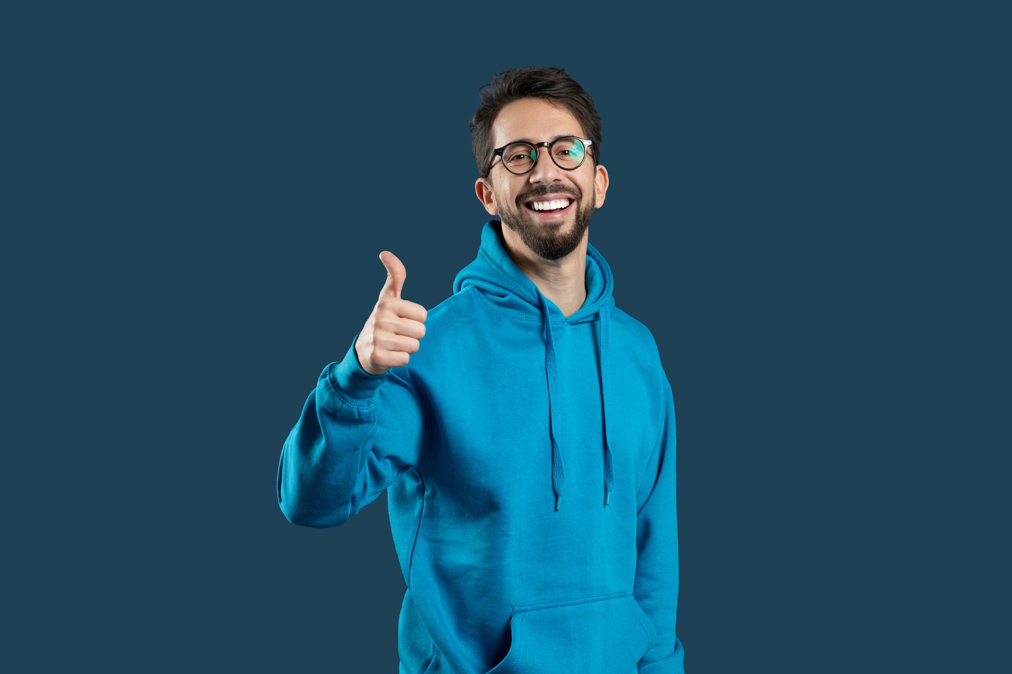 smiling-man-blue-hoodie-giving-thumbs-up-against-background